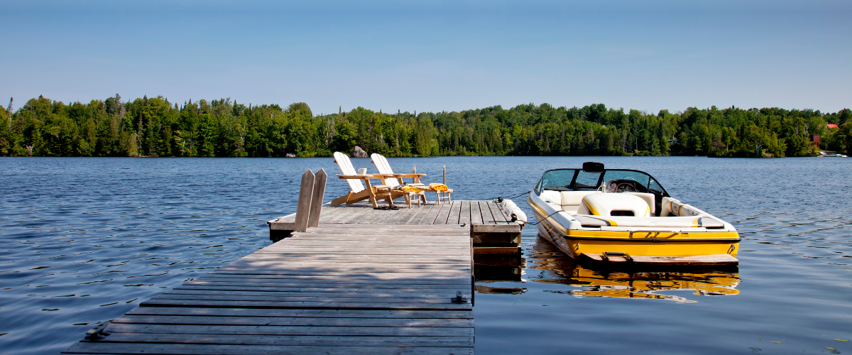 boat in the water on a lake next to a dock with chairs in the summer