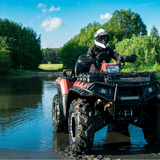 Person riding ATV through a puddle.