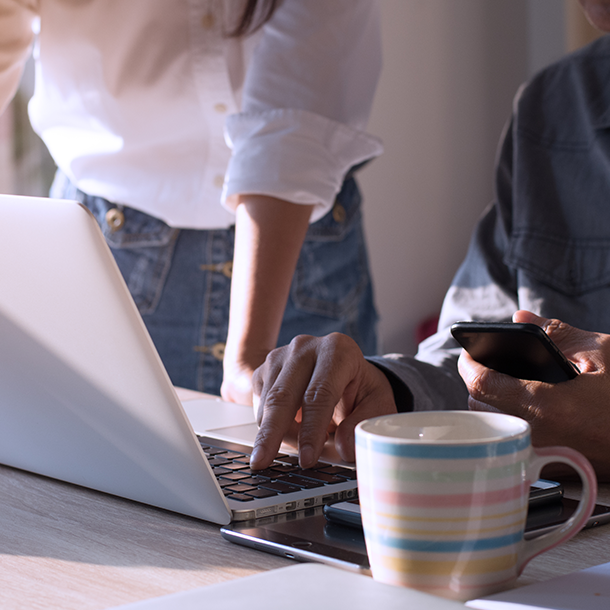 Two people with laptop computer and phone looking at devices together.